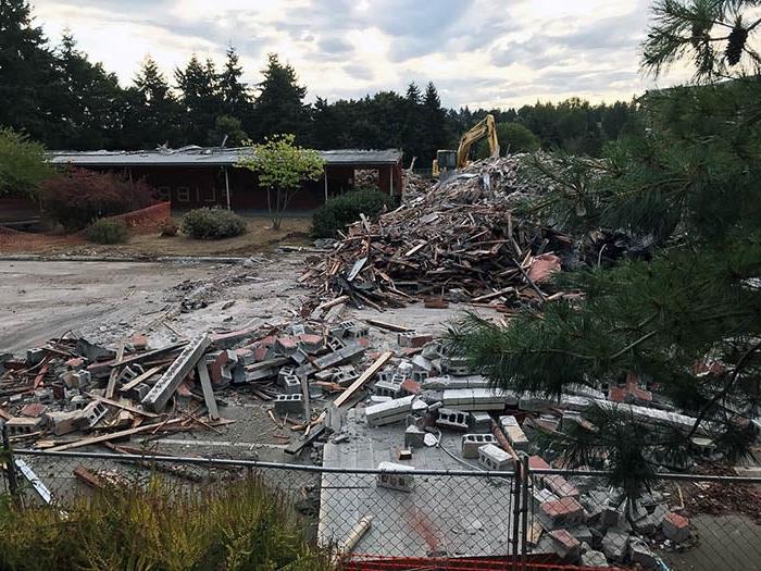 a large pile of debris including concrete blocks and wood in front of a partially demolished building