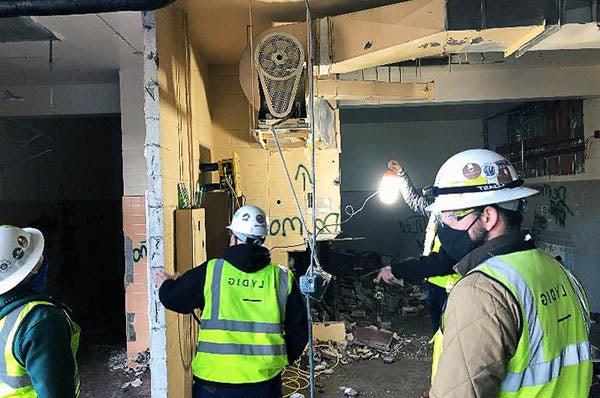 people in safety vests and hats looking at demolition