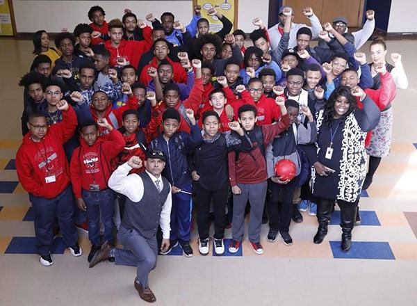 A group photo that includes Mia Williams and many students and educators with their right fist in the air