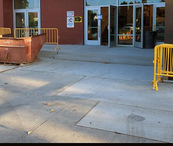 a concrete walkway leads to glass doors