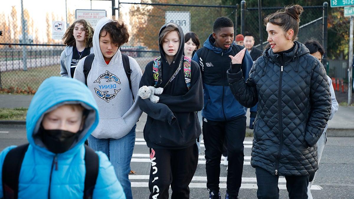 Students and adults walk together across a crosswalk