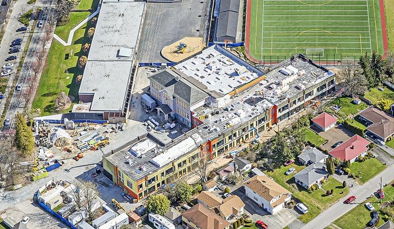 aerial of a buidling under construction with a playfield behind it