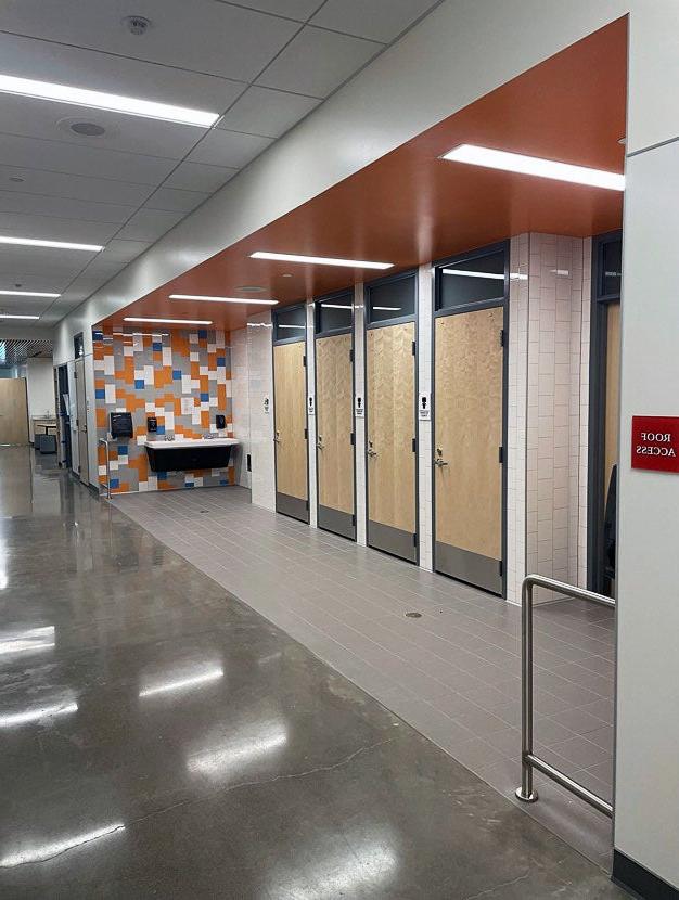 part of a hallway with doors set back from the path by tile. a sink hangs on the wall at one end