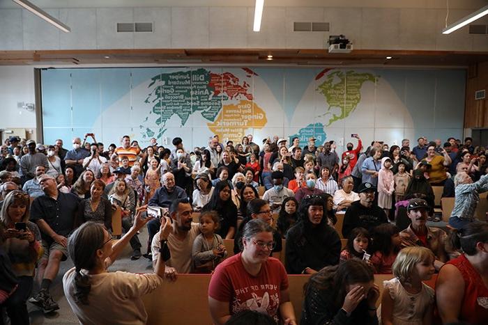 a large group of people in front of a wall with a map