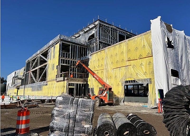 exterior of a 2, 3, and 4 story building under construction with materials in the foreground