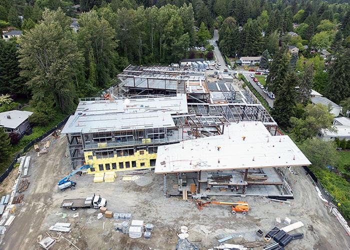 aerial view of a large building under construction with roofs in place in two areas and framing on others