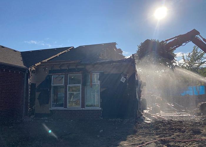 a loader is demolishing part of a brick building