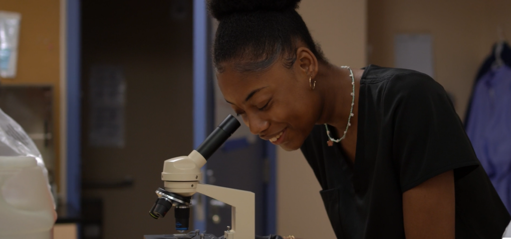 Student laughing at microscope