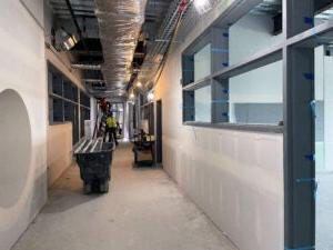 a hallway under construction with the ceiling open showing wiring and ducting