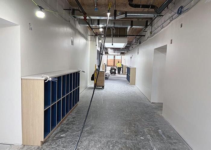 a wide hallway with an open ceiling and work lights