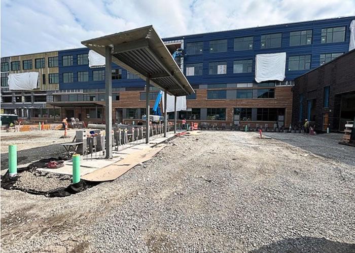 exterior of a building under construction with a canopy being installed in the middle of a gravel lot